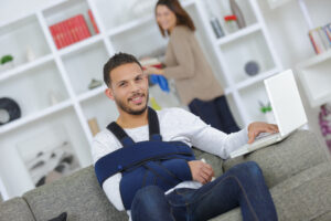 Man wearing shoulder sling using computer